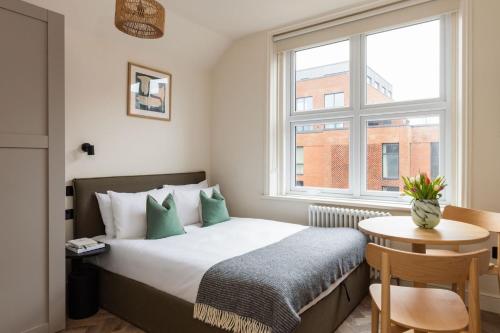 a bedroom with a bed with a table and a window at FiveM West Hampstead - South in London