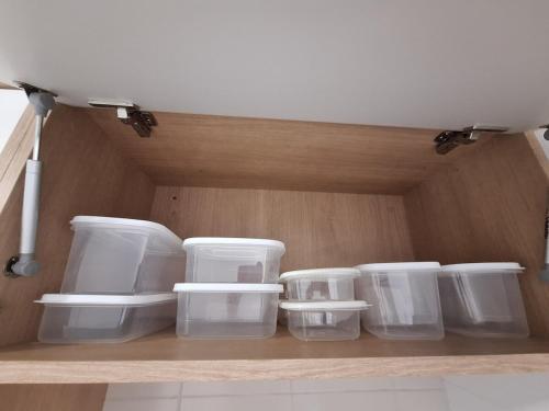 a group of plastic containers sitting on a shelf at Apartamento luxo, pertinho do Mar e lazer maravilhoso in Vila Velha
