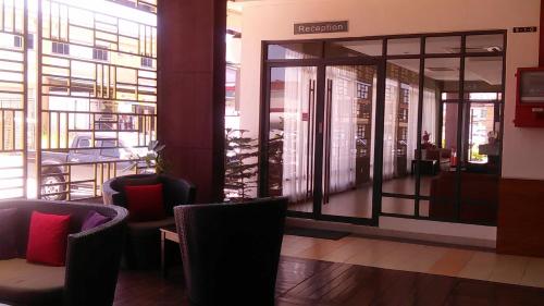 a lobby with chairs and a glass door to a restaurant at Gloria Swiss Hotel & Apartment Sandakan in Sandakan