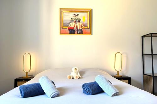 un ours en peluche assis sur un lit avec deux lampes dans l'établissement Le Music-hall - Vue Mer - Expo Sud, à Sainte-Adresse