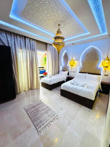 a large bedroom with two beds and a tv at Riad le marin Coucou beach in Agadir