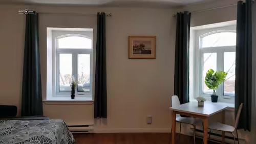 Un dormitorio con dos ventanas y una mesa y una cama. en Cozy Suite #3 in the Heart of DT Quebec with QB, en Quebec