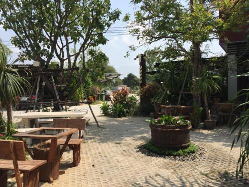 a patio with tables and benches and plants at Rayonghouse Resort in Rayong