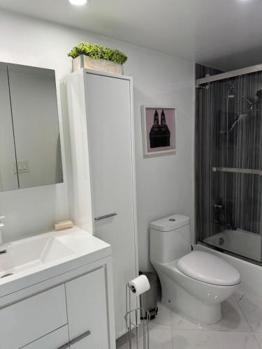 a white bathroom with a toilet and a sink at Trendy 1BD Condo 4 Mins to Beach in Sunny Isles Beach