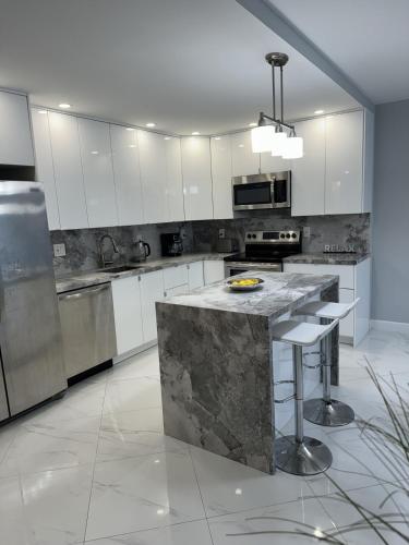 a kitchen with white cabinets and a marble counter top at Trendy 1BD Condo 4 Mins to Beach in Sunny Isles Beach