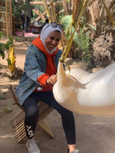 a woman is sitting on a bench with a chicken at Dahshour Today جولات ريفية in ‘Ezbet el-Khâṣṣa