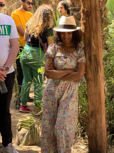 a woman wearing a hat standing next to a tree at Dahshour Today جولات ريفية in ‘Ezbet el-Khâṣṣa