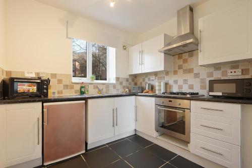 a kitchen with white cabinets and a microwave at Central Sheffield stylish stay in Sheffield
