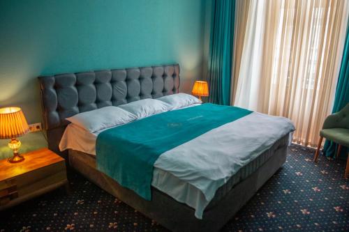 a bedroom with a large bed with a blue wall at Belona Hotel in Kutaisi