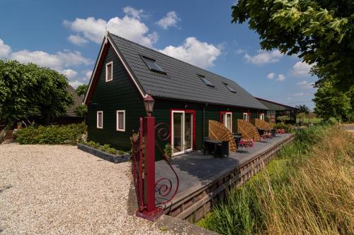 a house with a black roof and some chairs at Maria's hoeve Abcoude huisje 2 dichtbij Amsterdam in Abcoude