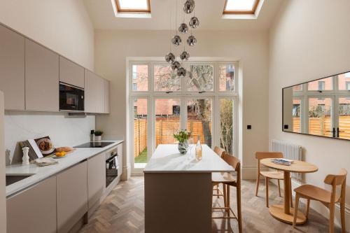 a kitchen with white cabinets and a table and chairs at FiveM West Hampstead - South in London