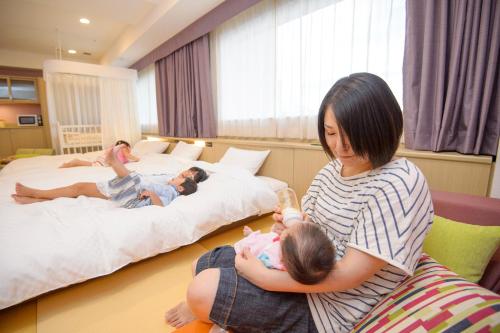 a woman sitting on a chair holding a baby at KAMENOI HOTEL Beppu in Beppu