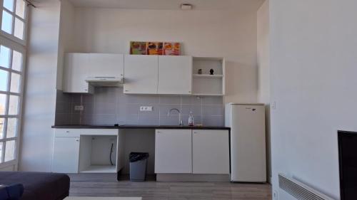  La cuisine est équipée de placards blancs et d'un réfrigérateur. dans l'établissement Superbe Logement Haussmannien Lumineux Bordeaux Centre, à Bordeaux