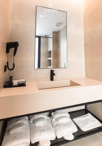 a bathroom with a sink and a shelf with towels at La Onda Hotel Durres in Durrës