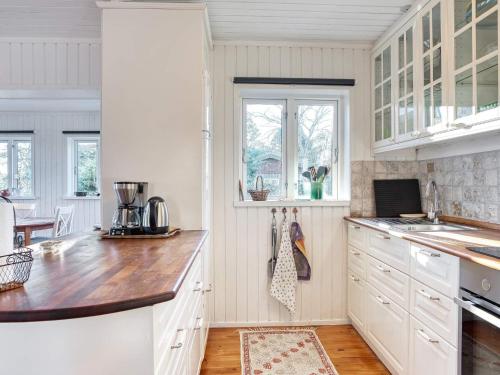 a kitchen with white cabinets and a wooden counter top at Modern Loft with Sea View - By Traum Ferienwohnungen in Allinge