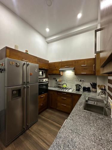 a kitchen with a stainless steel refrigerator and wooden cabinets at Nomad House in Kandana