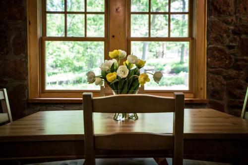 a vase of flowers on a table in front of a window at The Gate House- Autumn Retreat In Edmond, Ok in Edmond