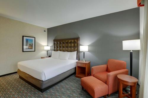 a hotel room with a bed and a chair at Drury Inn & Suites Charlotte Arrowood in Charlotte