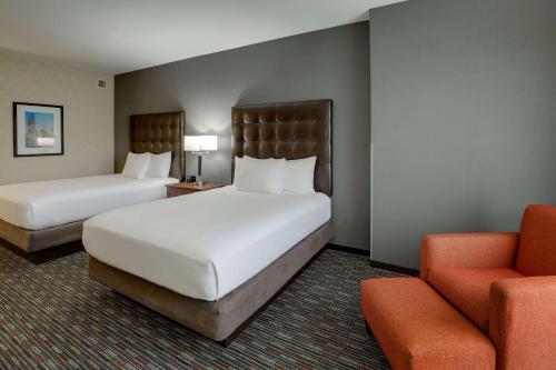 a hotel room with two beds and a chair at Drury Inn & Suites Charlotte Arrowood in Charlotte