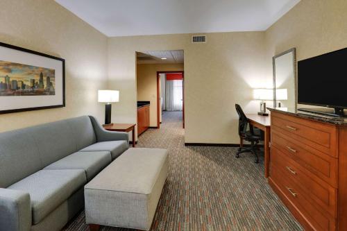 a living room with a couch and a tv and a desk at Drury Inn & Suites Charlotte Arrowood in Charlotte