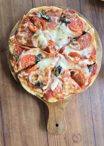 a pizza on a wooden plate on a table at Makarma Resort Lombok in Senggigi 
