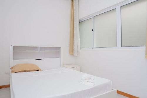 a white bedroom with a bed and a window at Your Escape Home in Praia in Praia