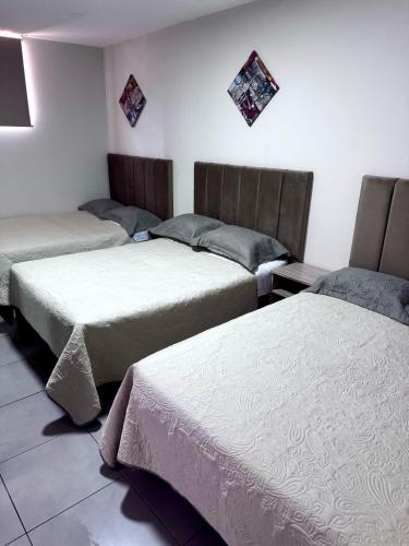 a room with three beds in a room at Hotel Gboss in Punta Hermosa