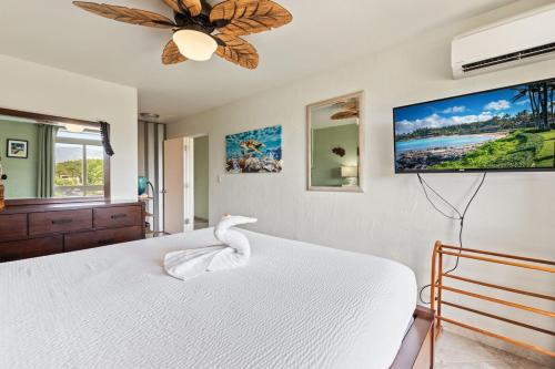 a bedroom with a white bed and a flat screen tv at Nani Kai Hale 403- Top floor 1 bedroom with AC & partial ocean view in Kihei