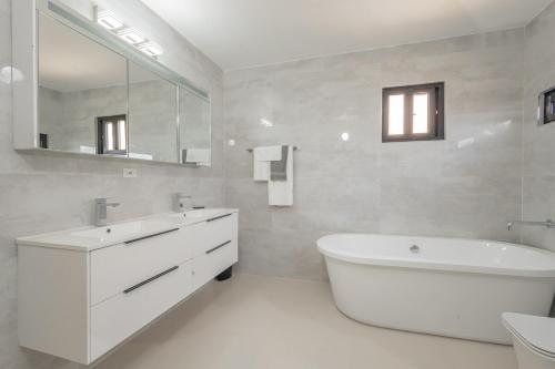 a bathroom with a large white tub and a sink at Modern, Spacious, 3BR Hill View Retreat, Central, Gated in Ocho Rios