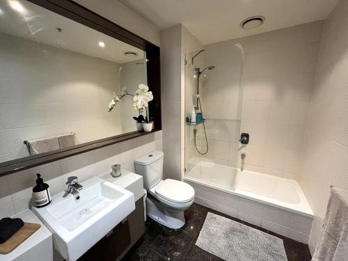 a bathroom with a sink and a toilet and a tub at Luxury 2BR Apartment, Pool, Gym & Free Parking in Melbourne