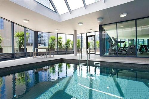 a large swimming pool in a large building with windows at Luxury 2BR Apartment, Pool, Gym & Free Parking in Melbourne