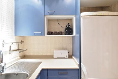 a kitchen with blue cabinets and a white refrigerator at Suites Barcelona Park G&uuml;ell in Barcelona