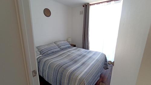 a small bedroom with a bed and a window at Departamento Condominio Parque Pucón in Pucón