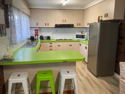 a kitchen with green counters and a refrigerator and stools at Wynyardway in Tumut