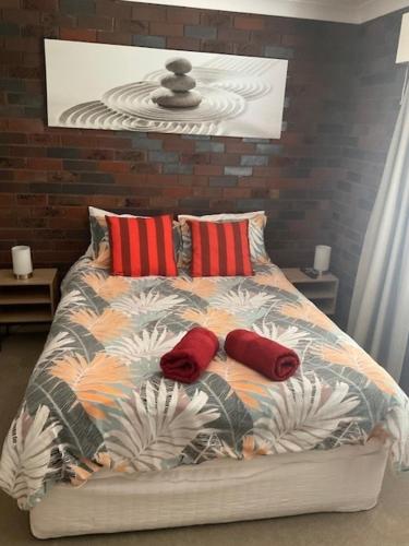 a bed with two red pillows on top of it at Wynyardway in Tumut