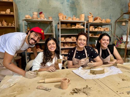 a group of people sitting around a table making pottery at VoyAca Hotel - Alfareria in Villa de Leyva