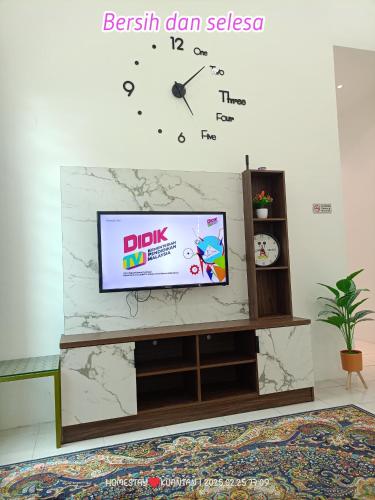 a tv on a wall with a clock on it at Teratai Inn Kempadang Kuantan in Kuantan