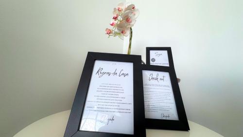 a table with two framed certificates and a vase with flowers at Casa em Aparecida 300m2 próximo ao Santuário Nacional in Aparecida