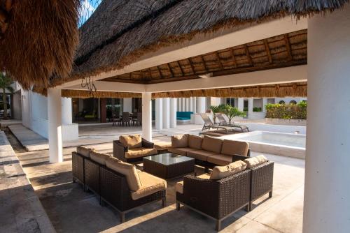 a patio with furniture and a thatched roof at Casa Linda, Paraíso de 4 recámaras en la Playa in Chicxulub