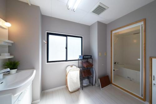 a bathroom with a sink and a shower and a mirror at おやど紀伊国屋銀屋町 in Nagasaki