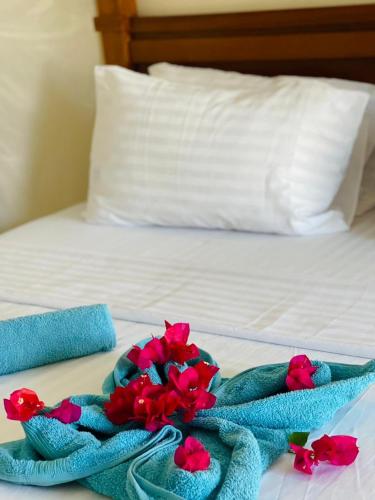 a bed with two towels and flowers on it at Linda's Little Lincoln in Watamu
