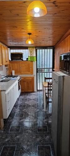 Una cocina con un refrigerador y una mesa dentro. en Departamento ILANAHO, en La Falda
