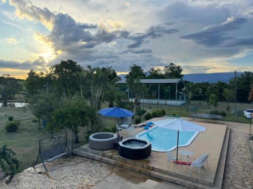 a swimming pool with an umbrella and a table and chairs at Sítio Santa Felicità entre Guaratinguetá e Aparecida do Norte in Guaratinguetá
