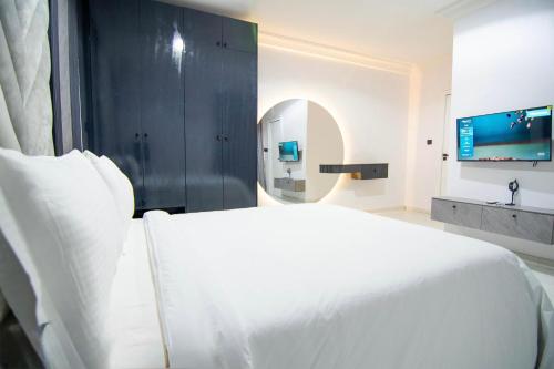 a bedroom with a large white bed and a mirror at De'Luxuries 2 Bedroom Apartment in Ikoyi with Pool in Lagos
