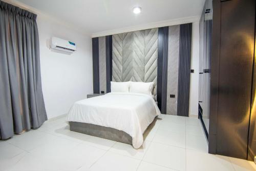a bedroom with a white bed and a wall at De'Luxuries 2 Bedroom Apartment in Ikoyi with Pool in Lagos