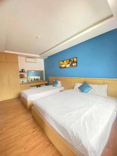a bedroom with two beds and a blue wall at DKD TRIO Hotel in Hue