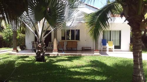 a house with palm trees in front of a yard at Casa de Playa en residencial las Veraneras San Fer in Los Cóbanos