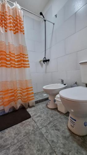 a bathroom with an orange and white shower curtain and a toilet at ItuRanch II in Ituzaingó