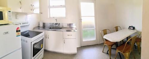 a white kitchen with a sink and a table at Cambrian Lodge Motel in Cambridge