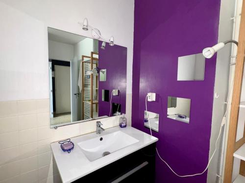 La salle de bains est pourvue d'un lavabo et d'un mur violet. dans l'établissement Appartement 2 chambres près plage, animaux admis - FR-1-323-309, à Saint-Jean-de-Monts